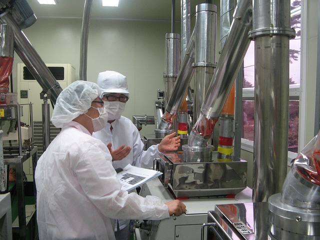 Dos personas en un laboratorio usando batas blancas y mascarillas protectoras.