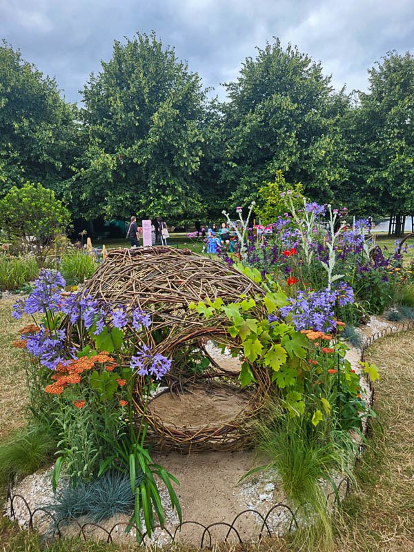 Arreglo floral incrustado en seto ornamental, destacando formas y texturas.